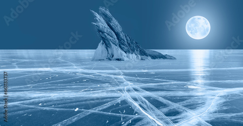 Fototapeta Naklejka Na Ścianę i Meble -  Ogoy island on winter Baikal lake with transparent cracked blue ice at sunrise , Full moon in the background - Baikal, Siberia, Russia 