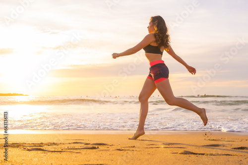 Fit woman jogging along a beach during sunset