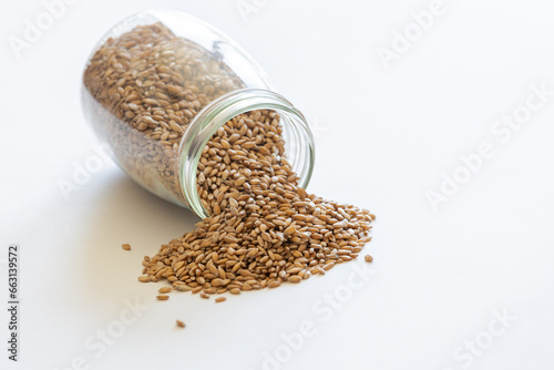 Spelt grains neatly stored in a glass jar against a clean white background, illustrating food storage