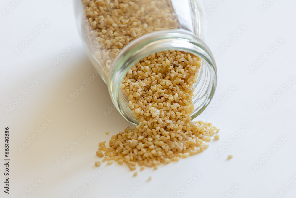 Bulgur grains neatly stored in a glass jar against a clean white background, illustrating food storage Bulgur grains neatly stored in a glass jar against a clean white background, illustrating food storage