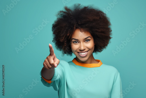 beautiful woman with afro expressing interest on blue background with index finger on side © Kien
