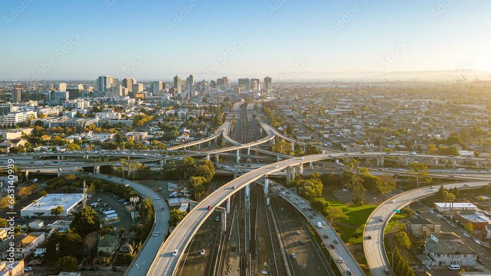 A drone view over the freeway cypress in Oakland, California during sunset with the downtown in the background. - obrazy, fototapety, plakaty 