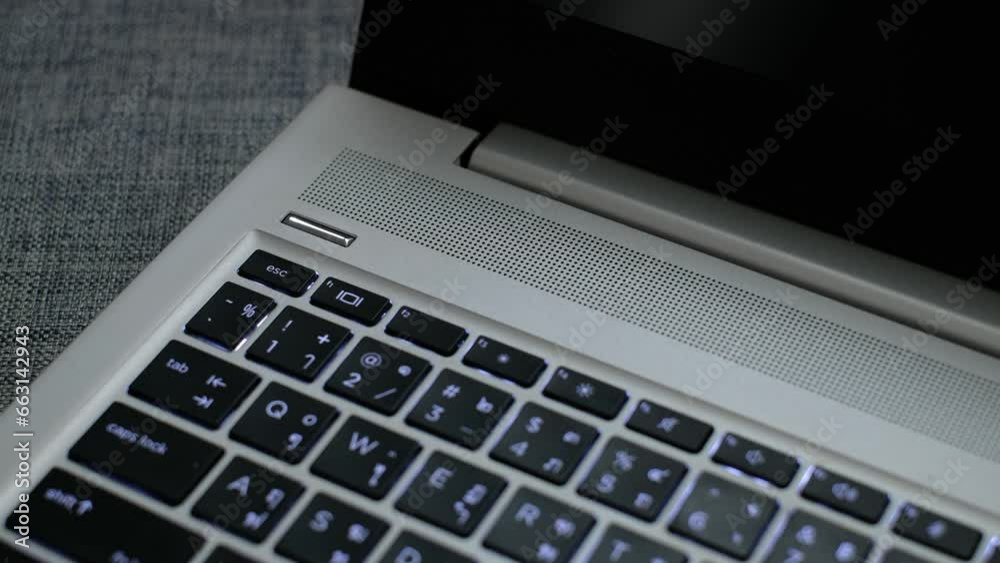 hand turning on laptop computer