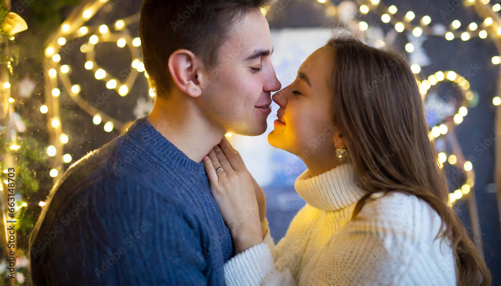 A youthful pair sharing a kiss beneath festive New Year's Eve lights