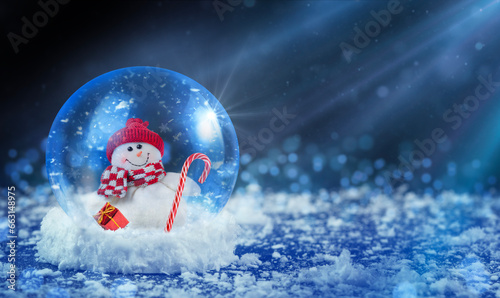Glass snow globe with snowman on dark snowing Christmas background  copy space.