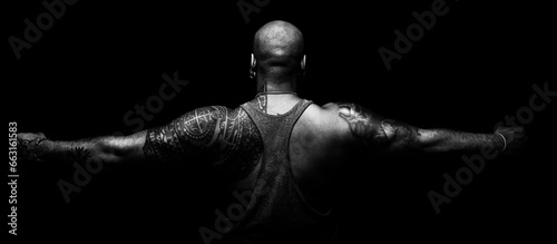 Back and arms of black man tattooed on black background in balnco and black