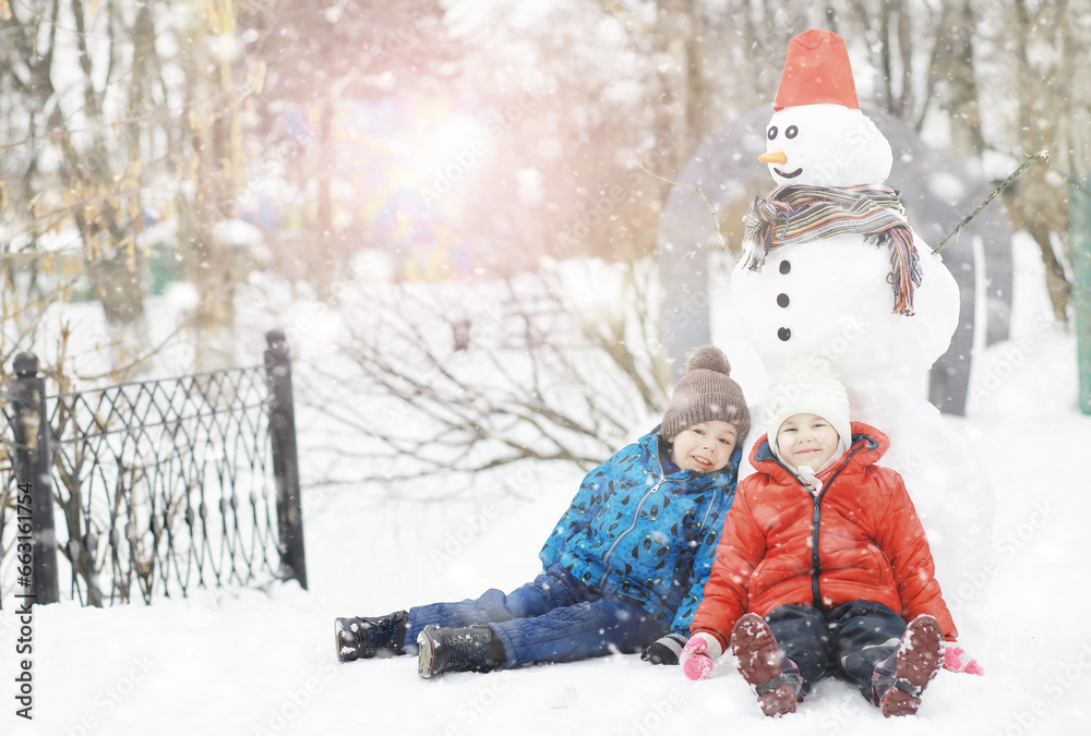 Children in the park in winter. Kids play with snow on the playground. They sculpt snowmen and slide down the hills. Children in the park in winter. Kids play with snow on the playground. They sculpt snowmen and slide down the hills.