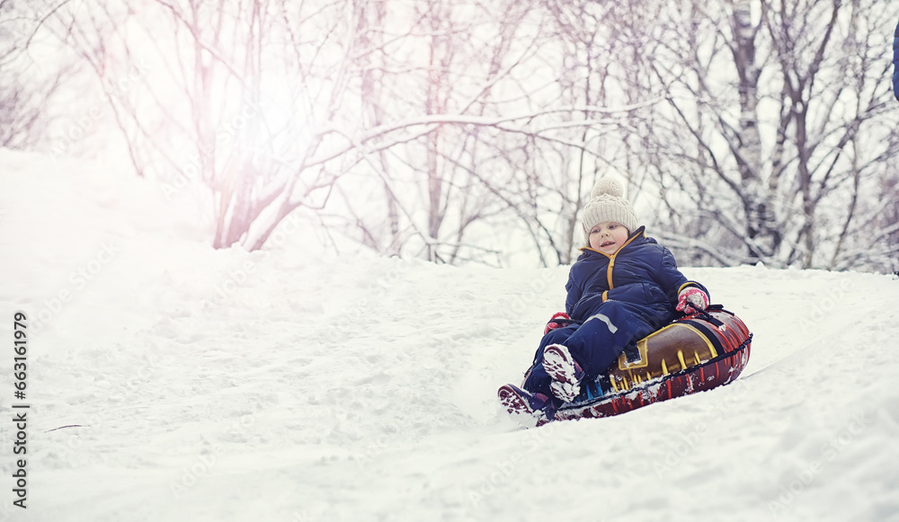 Children in the park in winter. Kids play with snow on the playground. They sculpt snowmen and slide down the hills.