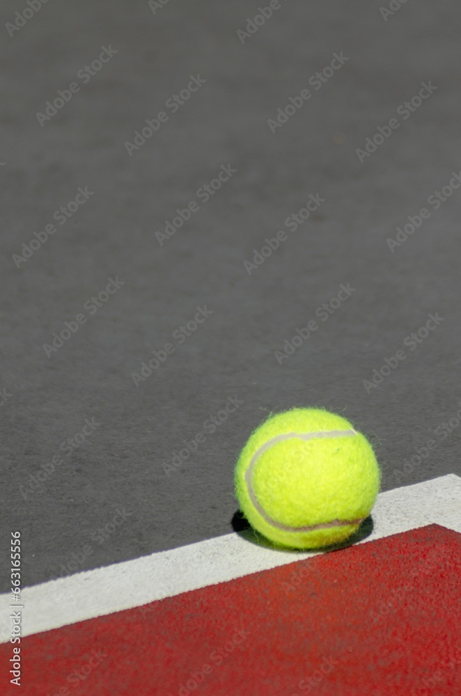 Vibrant yellow Tennis ball against the stark white court line