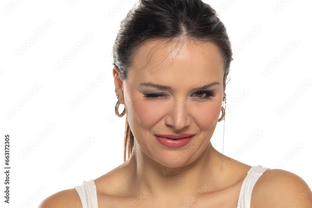 Headshot portrait of woman in 30s with makeup , smiling and winking on a white background