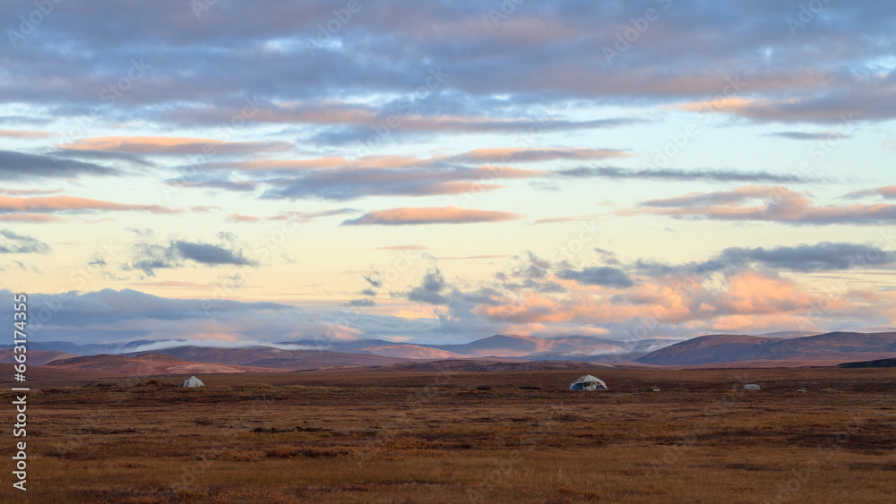 Morning panorama of the autumn tundra. Beautiful arctic landscape. Yarangi in the tundra (homes of nomadic reindeer herders). The traditional way of life of the indigenous people of Chukotka. Russia.