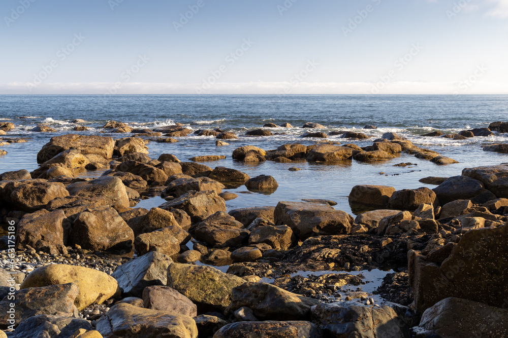 View from the shore to the sea at low tide. Rocky coast at low water. Stones and boulders on the seashore. Natural background for design. View from the shore to the sea at low tide. Rocky coast at low water. Stones and boulders on the seashore. Natural background for design.