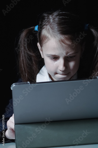 Lack of sleep as a result of studying at night may impair children's mood, increase stress and anxiety levels and decreased cognitive abilities. Young girl studies at night. Vertical image.