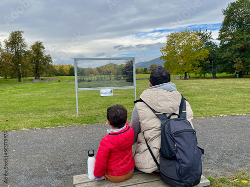 A father and son sit on a bench and look at a panorama with a photo. Duchcov, Czech Republic photo