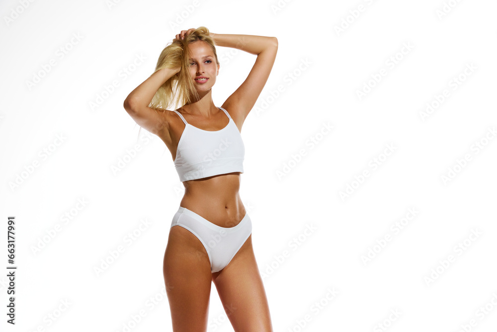 Happy, smiling, beautiful young girl with tanned, fit, slim body standing in underwear on white background. Concept of natural beauty, body and skin care, health, sport, wellness. Copy space for ad Happy, smiling, beautiful young girl with tanned, fit, slim body standing in underwear on white background. Concept of natural beauty, body and skin care, health, sport, wellness. Copy space for ad