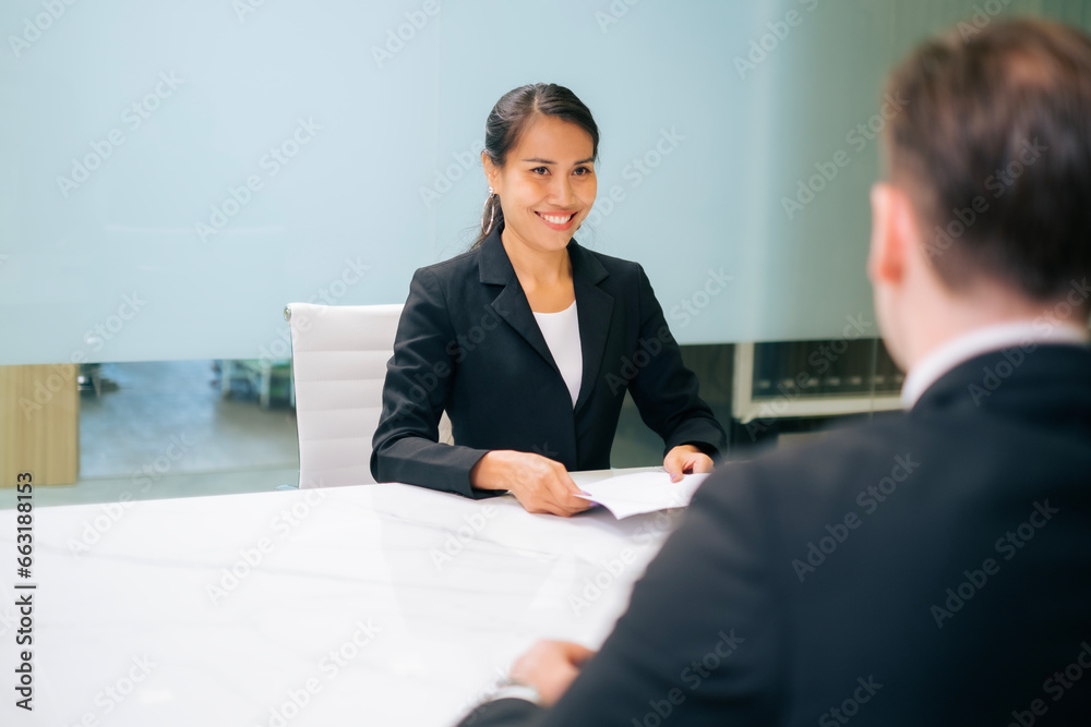 Middle age of Asian business woman looking and smile holding resume, while sitting in front of directors during corporate meeting or job interview, Business, career and placement concept Middle age of Asian business woman looking and smile holding resume, while sitting in front of directors during corporate meeting or job interview, Business, career and placement concept