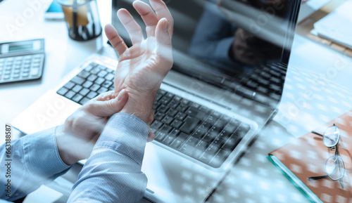 Businessman suffering from wrist pain; light effect