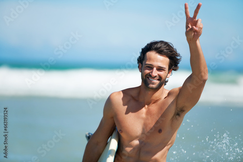 Surfing, portrait and happy man with peace hands at a beach for travel, freedom or adventure. Face, smile and male surfer with v sign at sea for water sports, training or summer vacation in Miami © Marine G/peopleimages.com