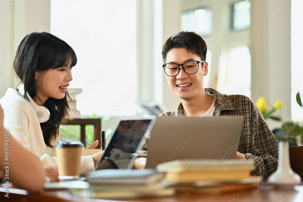 Friendly asian man student doing group project or preparing presentation on laptop with classmates Friendly asian man student doing group project or preparing presentation on laptop with classmates