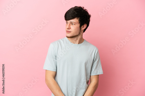 Young Russian man isolated on pink background looking to the side