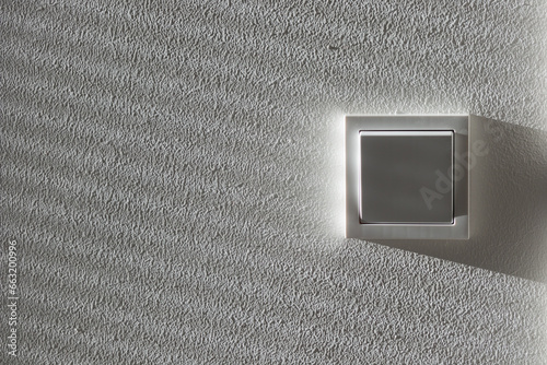 Light switcher on the white wall beneath rays of light