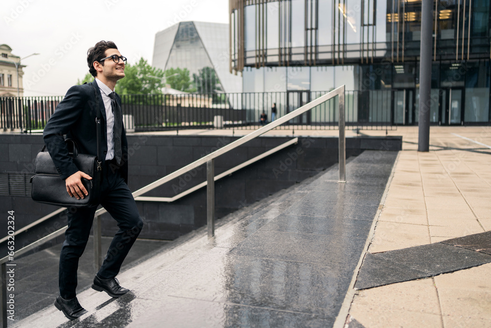 A trader is a man in a business suit going to a business center for a new job. The man is a businessman manager with a business bag with documents. A trader is a man in a business suit going to a business center for a new job. The man is a businessman manager with a business bag with documents.