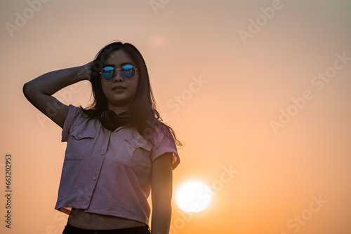 Asian glasses long hair girl is silhouette posting for camera shooting on the rooftop, top of building in twilight sunset time. photo