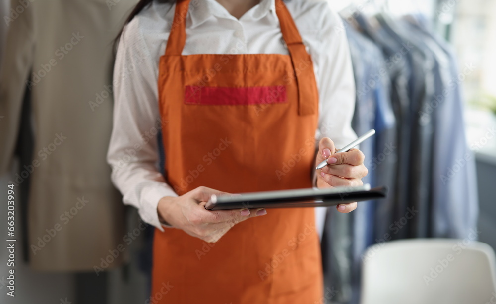 Close-up of dry cleaning company worker in uniform take order, high quality service, washing clothing from stains. Dry cleaning, laundry, cleanup concept