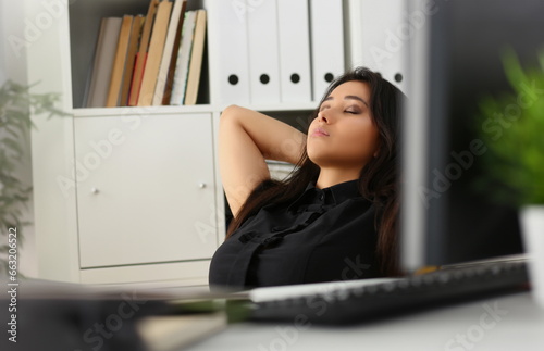 Portrait of female office worker having break, napping with closed eyes at work. Lazy clerk at work, kill time, tired. Job, pause, break, sleepy concept photo