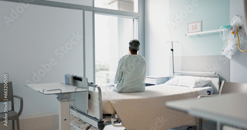 Back  healthcare and a woman on a hospital bed by the window in recovery or waiting for a visit. Medical  cancer and a patient thinking about the future of medicine in a health clinic for treatment