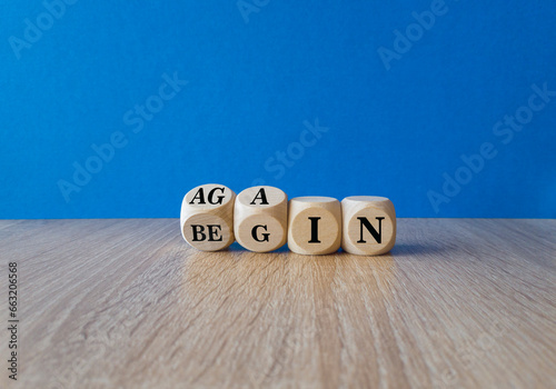 Begin again symbol. Turned wooden cubes and changes the words begin to again. Beautiful blue background, wooden table. Business and begin again concept. Copy space.