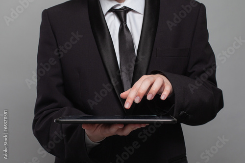 Business person working online with a digital tablet on grey background