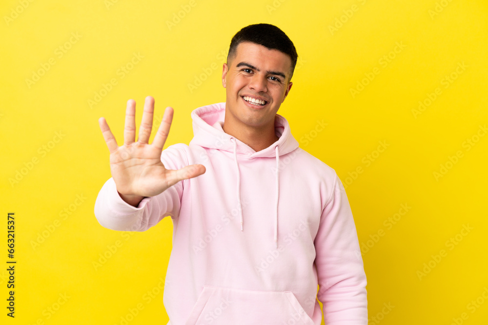 Young handsome man over isolated yellow background counting five with fingers Young handsome man over isolated yellow background counting five with fingers