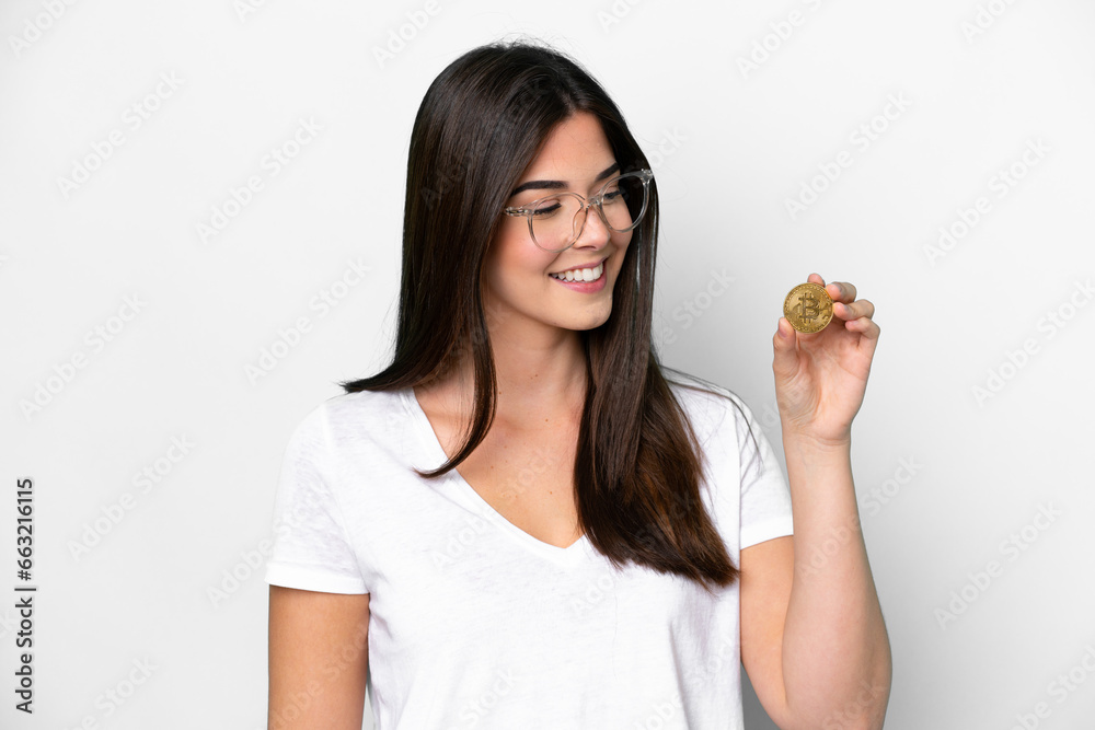 Young Brazilian woman holding a Bitcoin isolated on white background with happy expression Young Brazilian woman holding a Bitcoin isolated on white background with happy expression