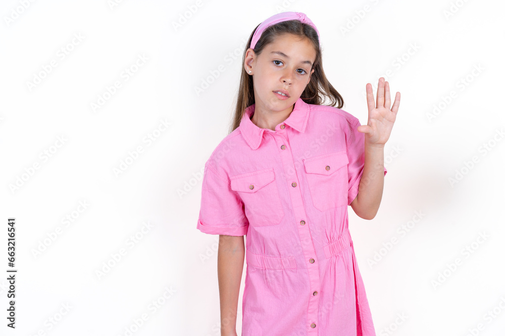 Beautiful little kid girl wearing pink dress Waiving saying hello happy and smiling, friendly welcome gesture. Beautiful little kid girl wearing pink dress Waiving saying hello happy and smiling, friendly welcome gesture.