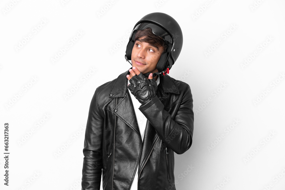 Young man with a motorcycle helmet isolated on white background looking up while smiling Young man with a motorcycle helmet isolated on white background looking up while smiling