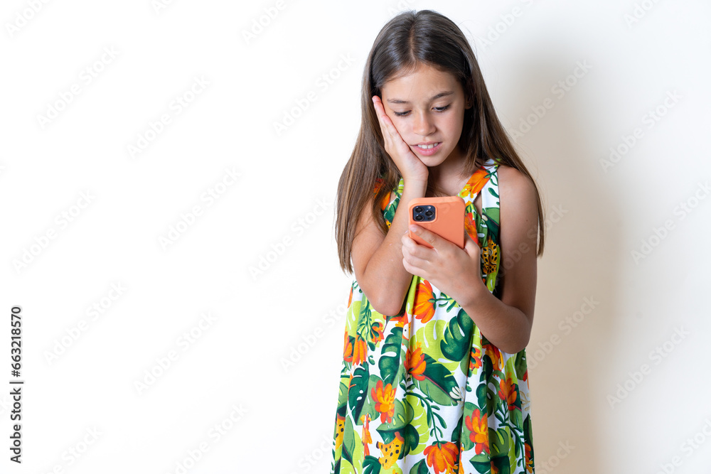 Beautiful kid girl wearing floral dress holding in hands mobile phone and looking aside with dreamy look. Beautiful kid girl wearing floral dress holding in hands mobile phone and looking aside with dreamy look.
