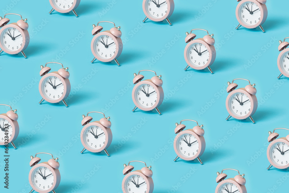 Trendy pattern made with pink alarm clocks on bright blue background Trendy pattern made with pink alarm clocks on bright blue background