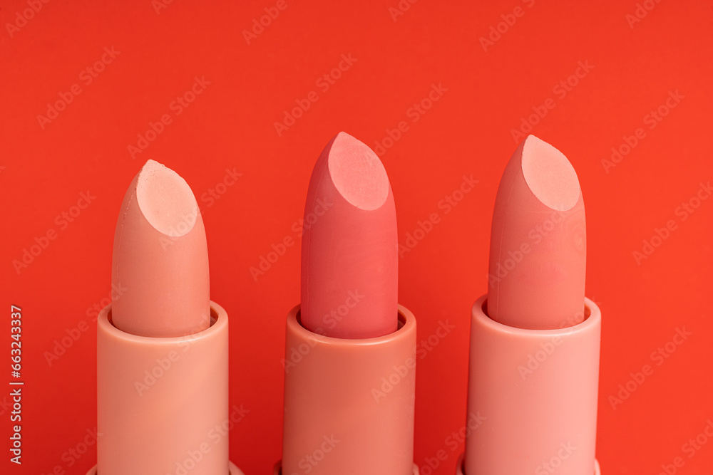 A row of different colors lipsticks on a red background