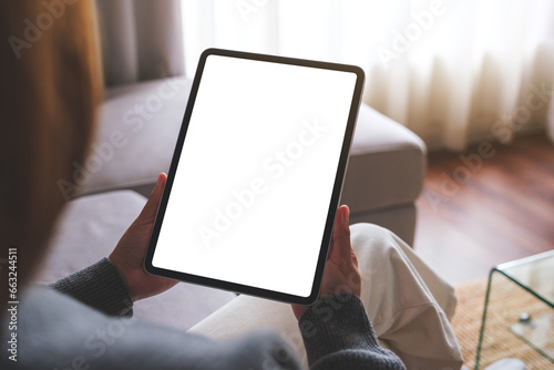 Fototapeta Naklejka Na Ścianę i Meble -  Mockup image of a woman holding digital tablet with blank desktop screen while sitting on a sofa at home
