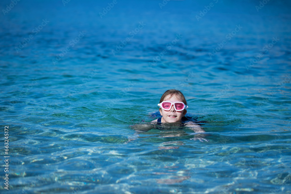 little girl plays and swims in the water in the sea