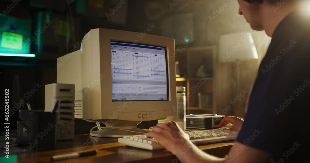 Caucasian Male Stock Trader Using Old Desktop Computer With Financial Candlestick Chart In Retro Garage. Man Analyzing Market Orders Before Entering Trade, Starting Investment Fund In Nineties.