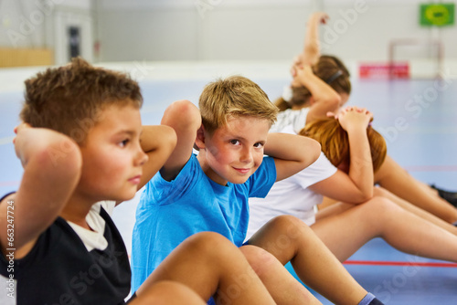 Group of children doing sit-ups in elementary school gym