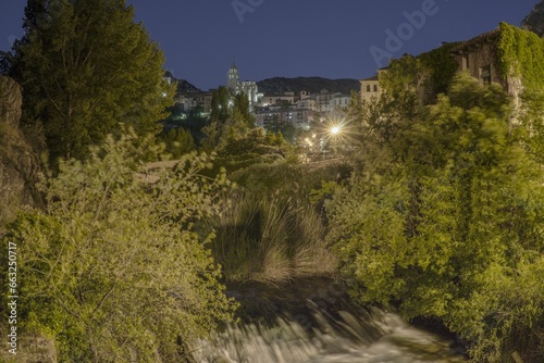 Views of the medieval village of Albarracin at night and in the foreground of the Guadalaviar river