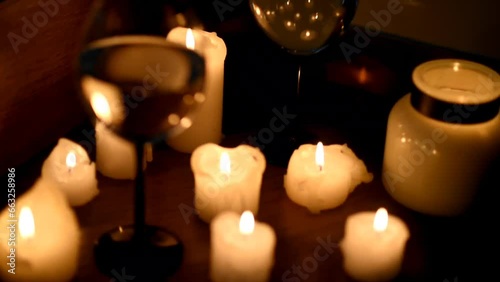 A glass of wine and candles in the dark. The focus shifts from the glass to the candles and the image is blurred in the side. Romantic dinner