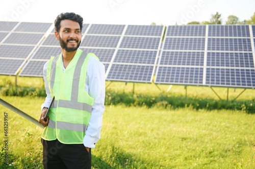 Portrait young indian technician or manager wearing formal cloths standing with solar panel. renewable energy, man standing crossed arm, copy space © Serhii