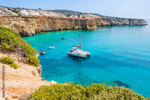 View of catamaran boat on sea coast near Tsigrado beach, Milos island, Cyclades, Greece photo