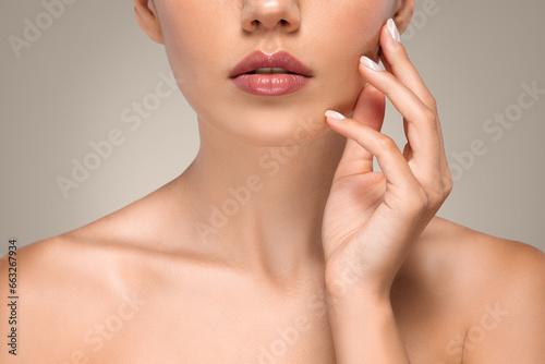 Calm millennial caucasian lady with perfect soft skin touching hands to face