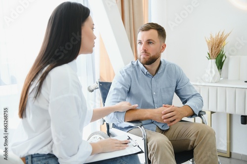 Portrait of female psychiatrist interviewing handicapped man during therapy session, copy space.