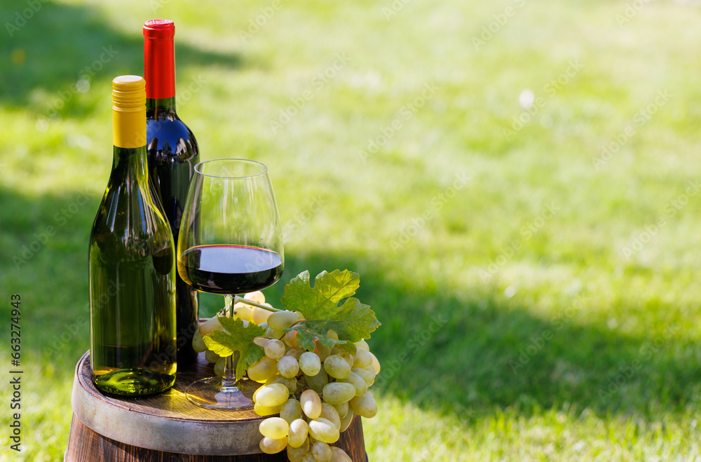 Wine bottles and grape on barrel